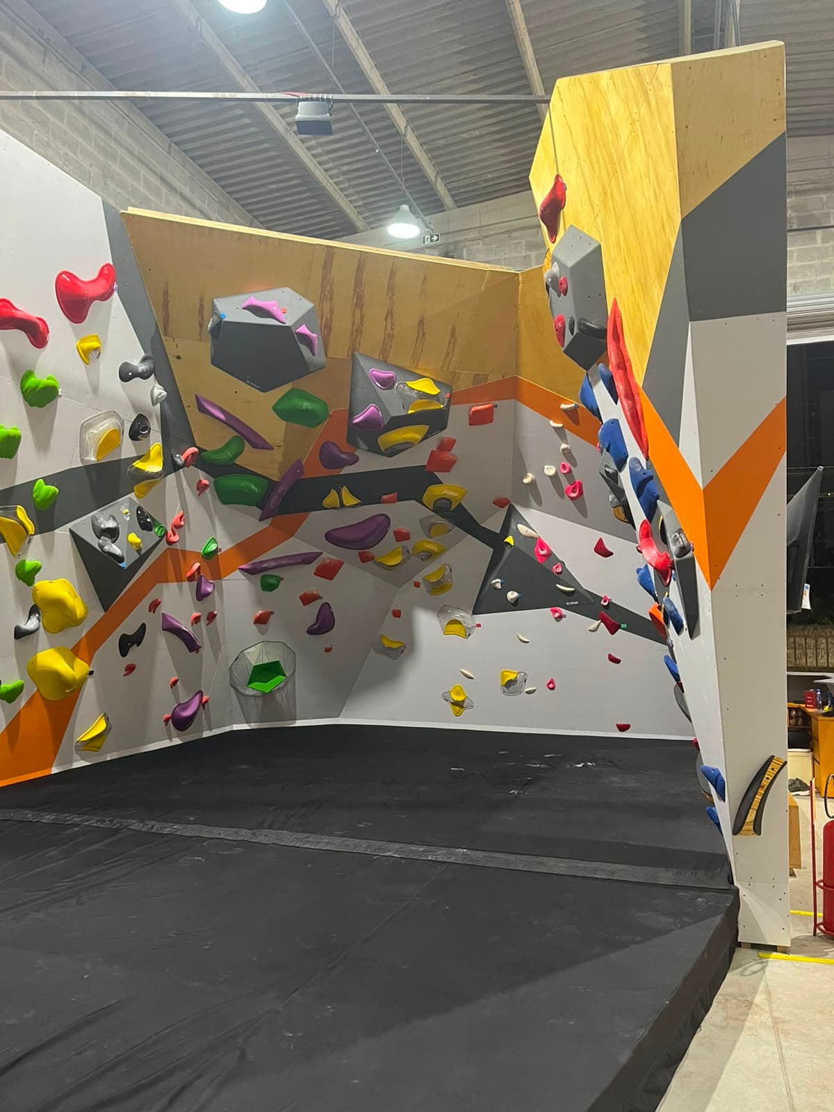 Setor de boulder da B-ROCK com colchões de queda e prismas amarelos